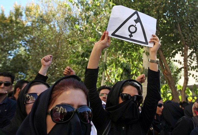 Iranian women, hiding their faces not to be identified, shout slogans during a protest in front of the judiciary building on October 22, 2014 in Isfahan, 450 kilometres south of Tehran, in solidarity with women injured in a series of acid attacks. Around 1,000 people took part in the protest calling for better security with banners and placards demanding action after four women have been maimed by assailants on motorcycles who threw acid on them. The acid attacks have prompted speculation on social networks that the victims were targeted because they were