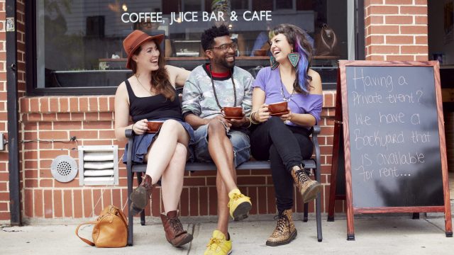 Friends sitting outside coffee shop on city street