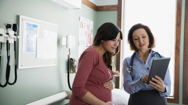 Doctor and pregnant woman looking at digital tablet