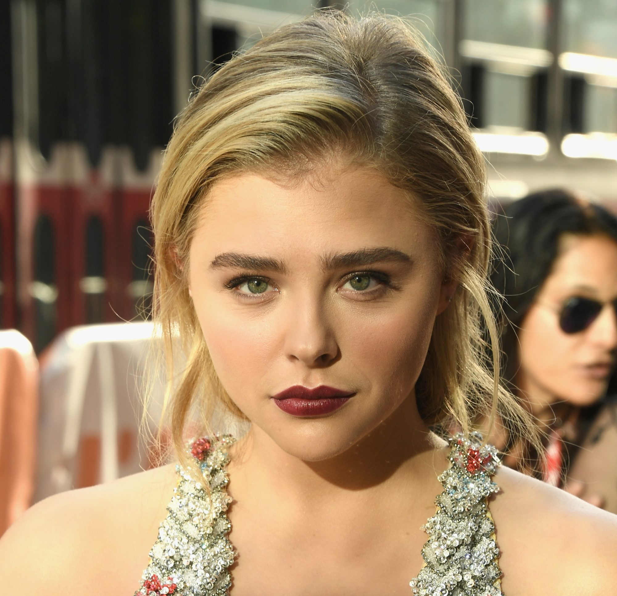 Chloe Grace Moretz wears gold earrings, a white lace print pattern