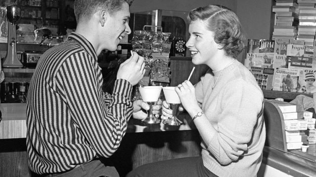 Teen Couple On Stools At Soda Fountain Drinking Sh