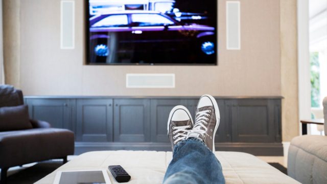 Womans feet on ottoman watching TV