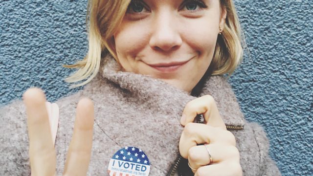 Smiling Beautiful Woman Wearing Campaign Button Gesturing Peace Sign