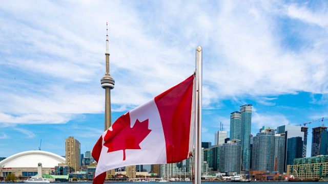 Canadian flag and the Toronto skyline. The flags waves from