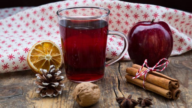 Glass of mulled wine, apple, cloth, walnut, cinnamon sticks and cinnamon stars