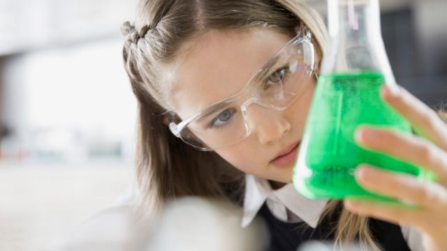 School girl examining liquid in beaker