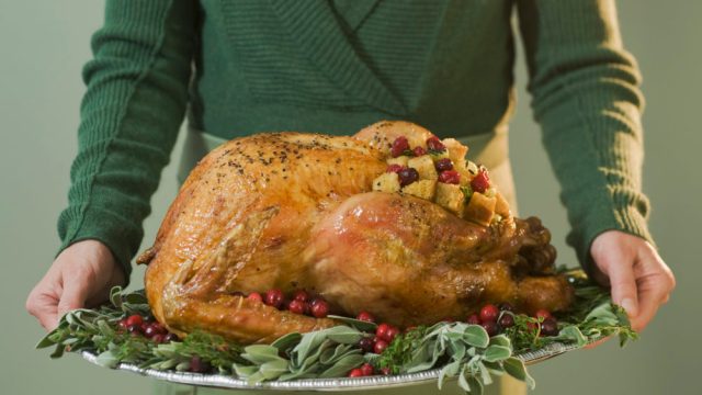 Man holding Thanksgiving turkey on decorated platter