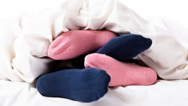 Pink and blue stocking feet of loving couple in bed