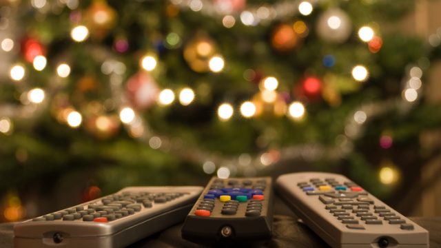 Remote controls in front of lit christmas tree