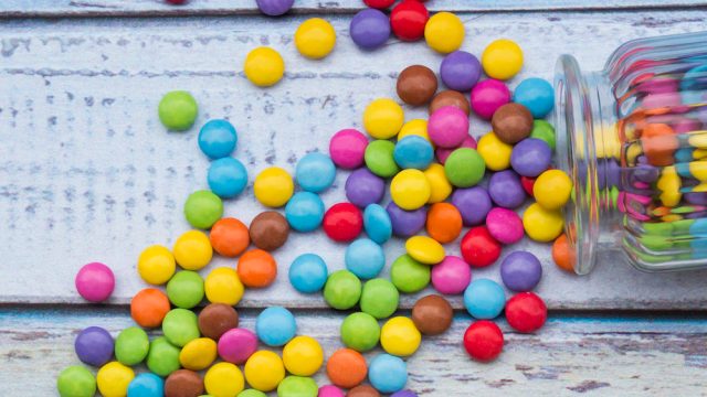Smarties and candy jar on light blue wood
