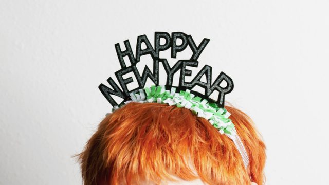 A woman wearing a party tiara with Happy New Year on it, top of head
