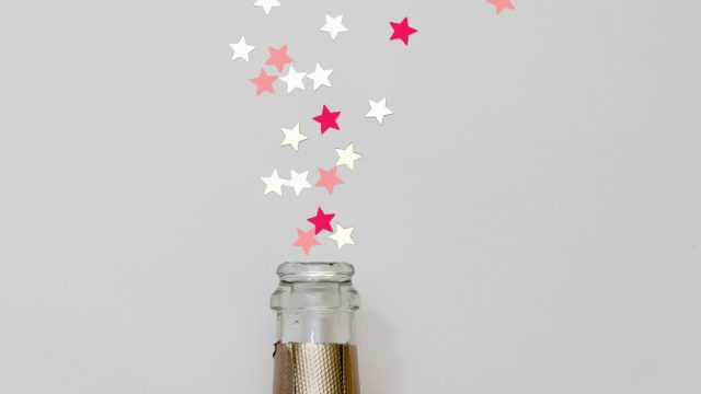 Star shaped confetti spraying out of a champagne bottle