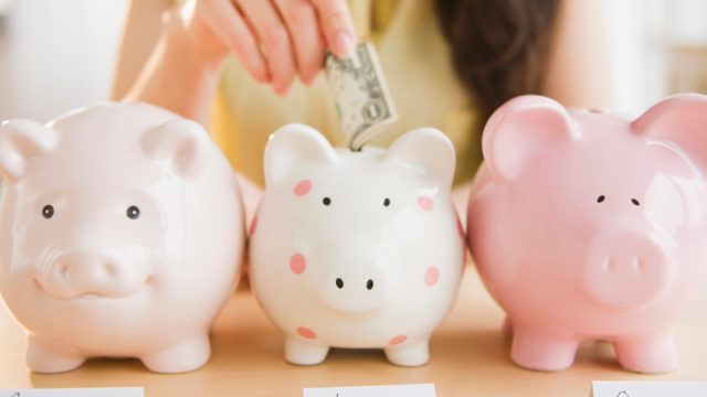 Mixed race woman putting money into piggy bank