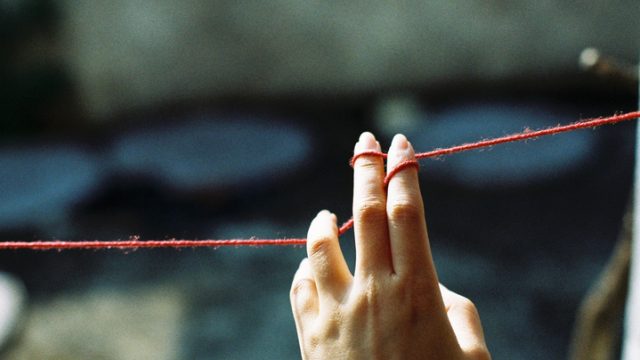 Cropped Image Of Woman Hand Holding Wool String On Sunny Day