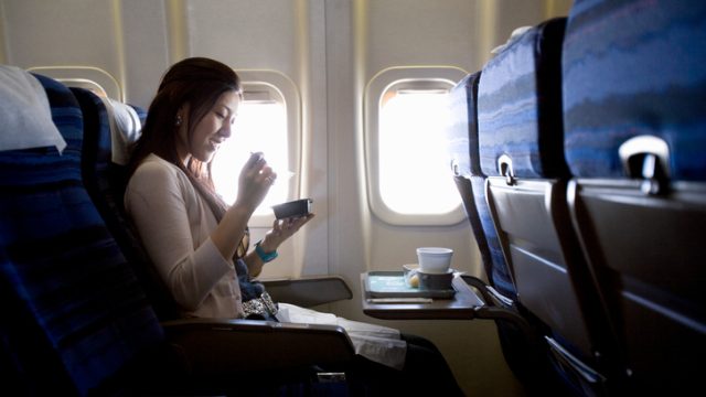 Woman eating meal in airplane