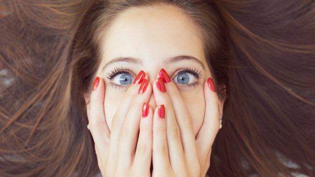 Beautiful woman with hands on face and red nails
