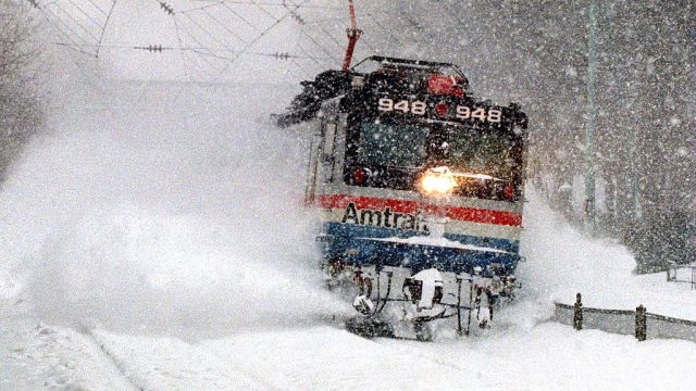 An Amtrak train blasts through a snow drift