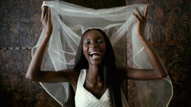 Young bride raising veil, laughing, portrait