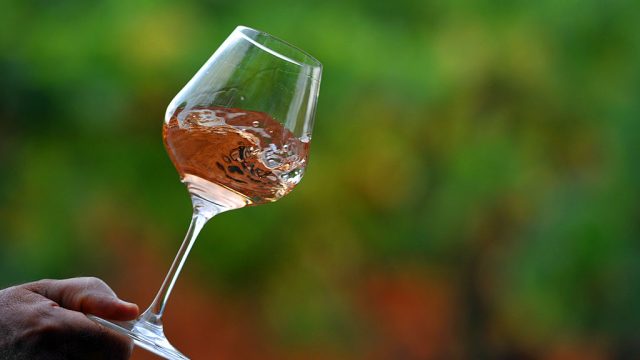 man holds glass of rose wine