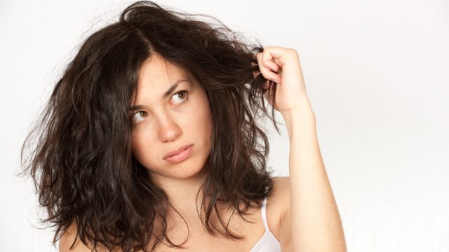 Woman clutching wavy dark hair over a white background
