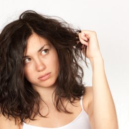 Woman clutching wavy dark hair over a white background
