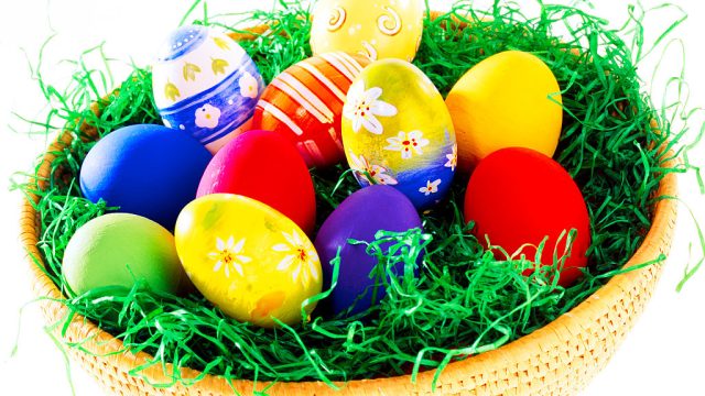 colored easter eggs in basket artificial grass