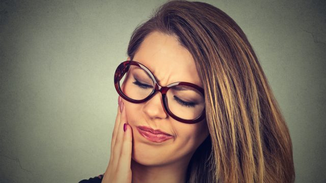 woman in glasses with sensitive toothache pain