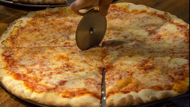 a pizza pie being sliced with a pizza cutter