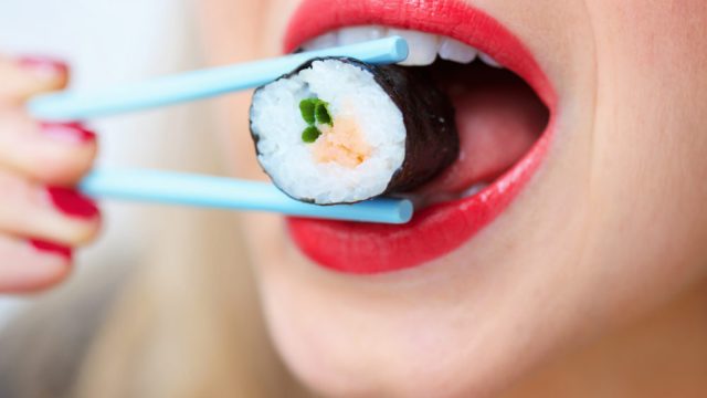woman eating sushi with chop sticks , close up