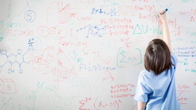 kid writing math equations on a white board