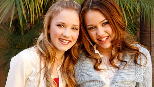 Emily Osment and Miley Cyrus at an event smiling