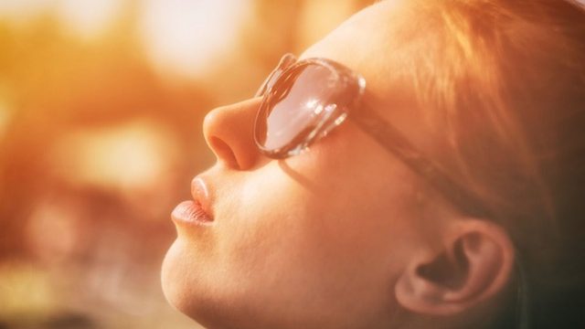 Woman looking into the sun with sunglasses