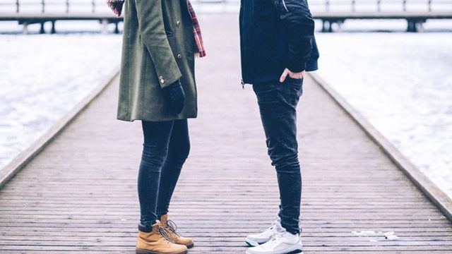 Two people stand facing each other on a dock