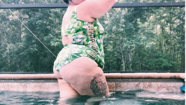 Plus-sized lifeguard Courtney Harrough poses poolside in a green bathing suit