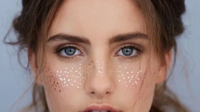A model wears metallic foil freckles.
