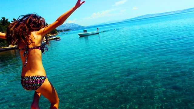 Young woman jumping into the ocean