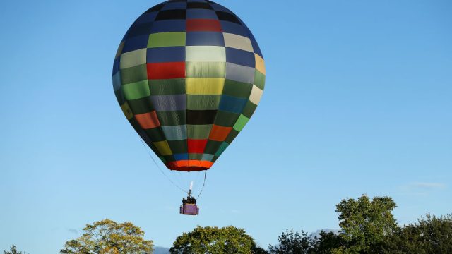 checkered Hot Air Balloon flying over trees