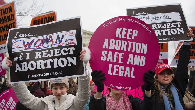 A pro-choice activist (C) demonstrates in the middle of pro-life activists as they demonstrate in front of the US Supreme Court during the March For Life in Washington, DC, January 27, 2017.