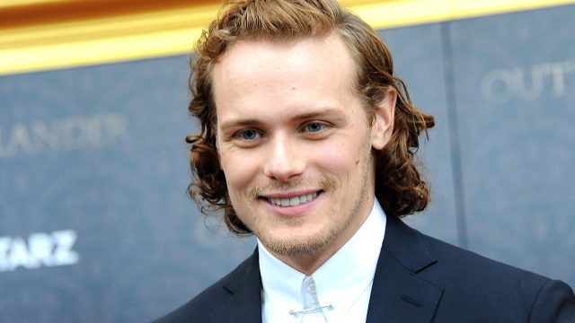 A close-up of actor Sam Heughan in a suit on the red carpet