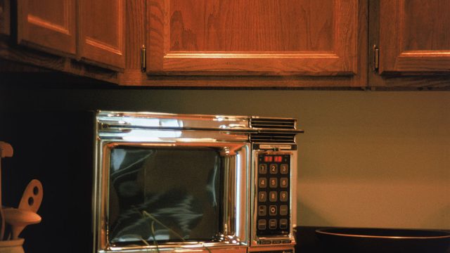 A chrome Radarange by Amana microwave oven features a keypad and digital display screen and sits on a kitchen countertop, 1970s.