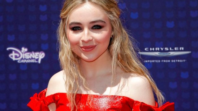 Sabrina Carpenter wears a red off-the-shoulder top or dress on the red carpet