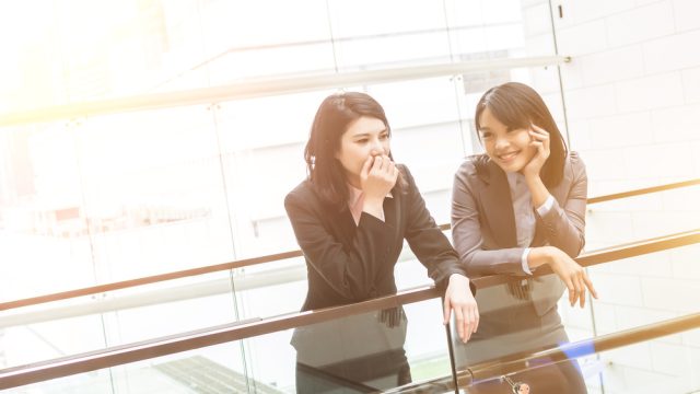 Two Asian women smiling at the office
