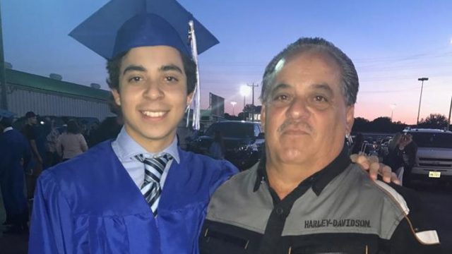 A father and son pose together at a high school graduation