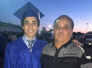 A father and son pose together at a high school graduation