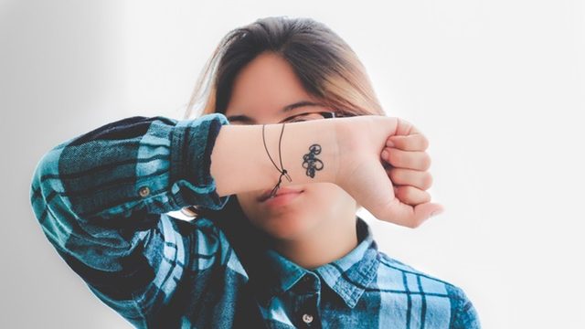 Woman holding up her wrist tattoo