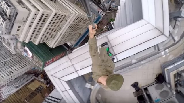 guy rides hoverboard on building ledge