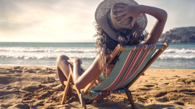 Woman at the beach sitting in a chair.
