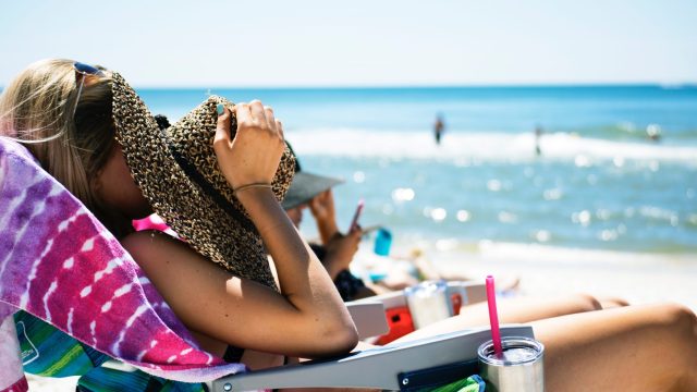 girl on the beach shields face from sun