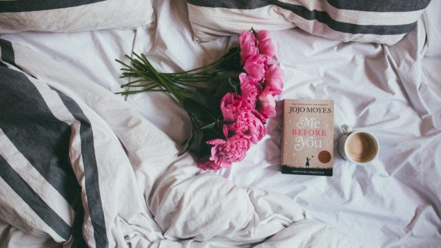 pink flowers book and cup of coffee sitting on a bed