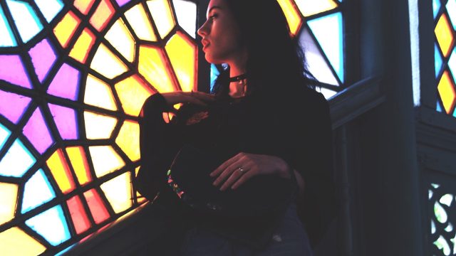Woman standing while looking through multicolored window